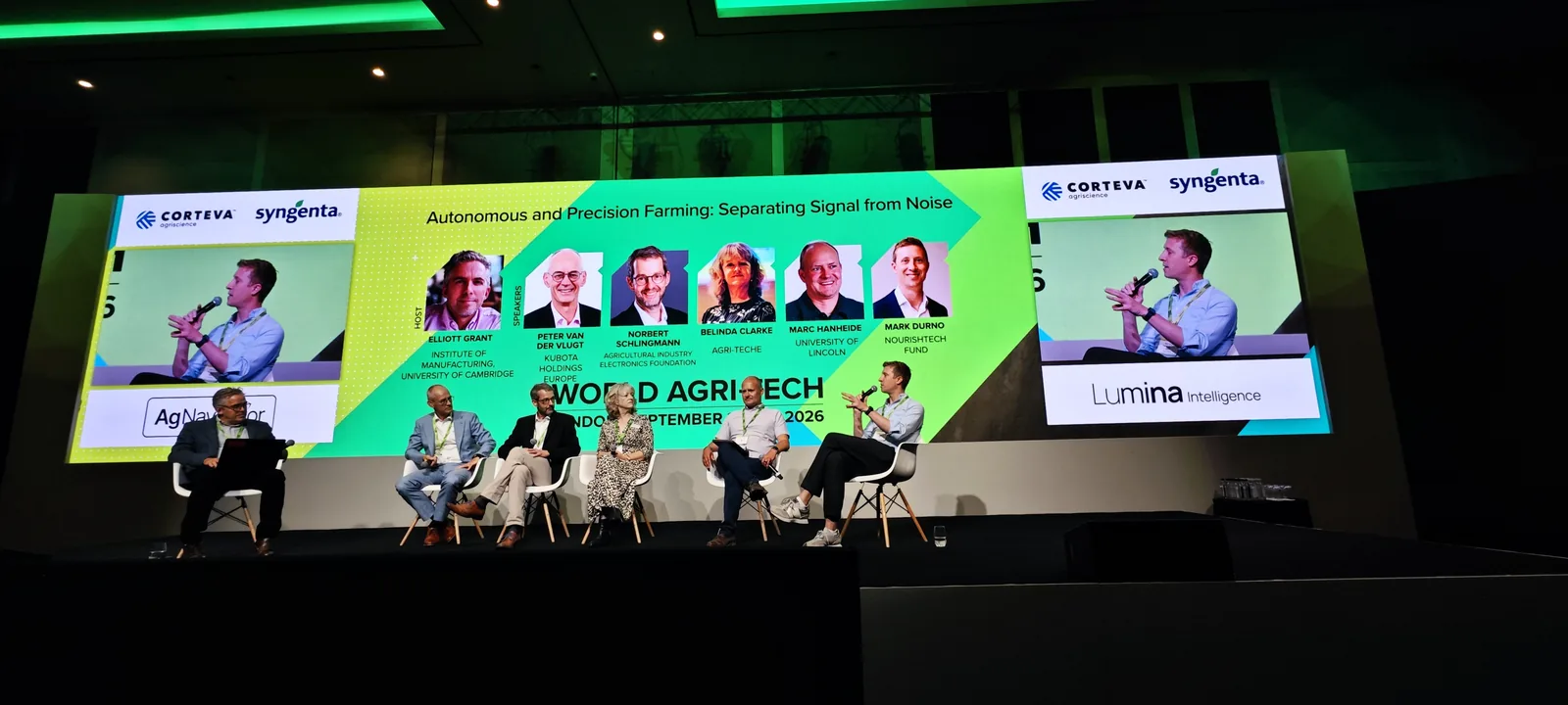 A panel of speakers seated on the summit stage under two large screens, with the World Agri-Tech backdrop and dimmed hall around them.