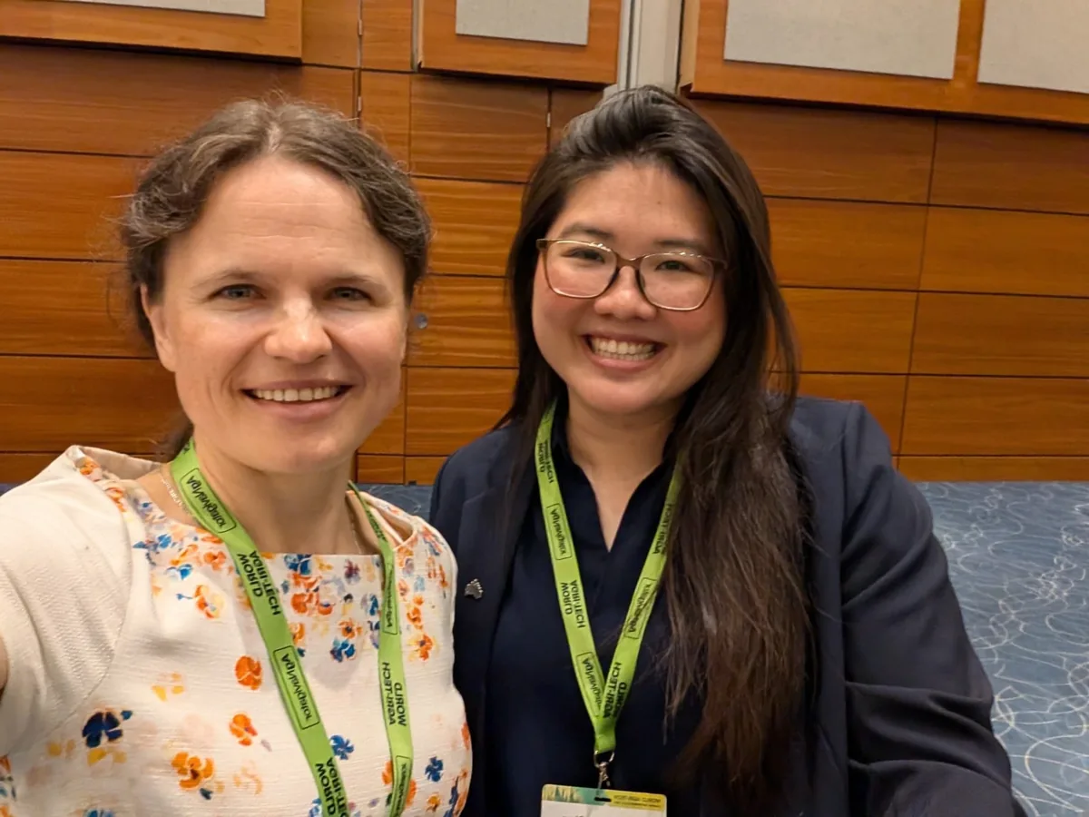 Dr. Maryna Kuzmenko and Ming Fung Chua, both with green summit lanyards, smiling in a selfie in the conference foyer.