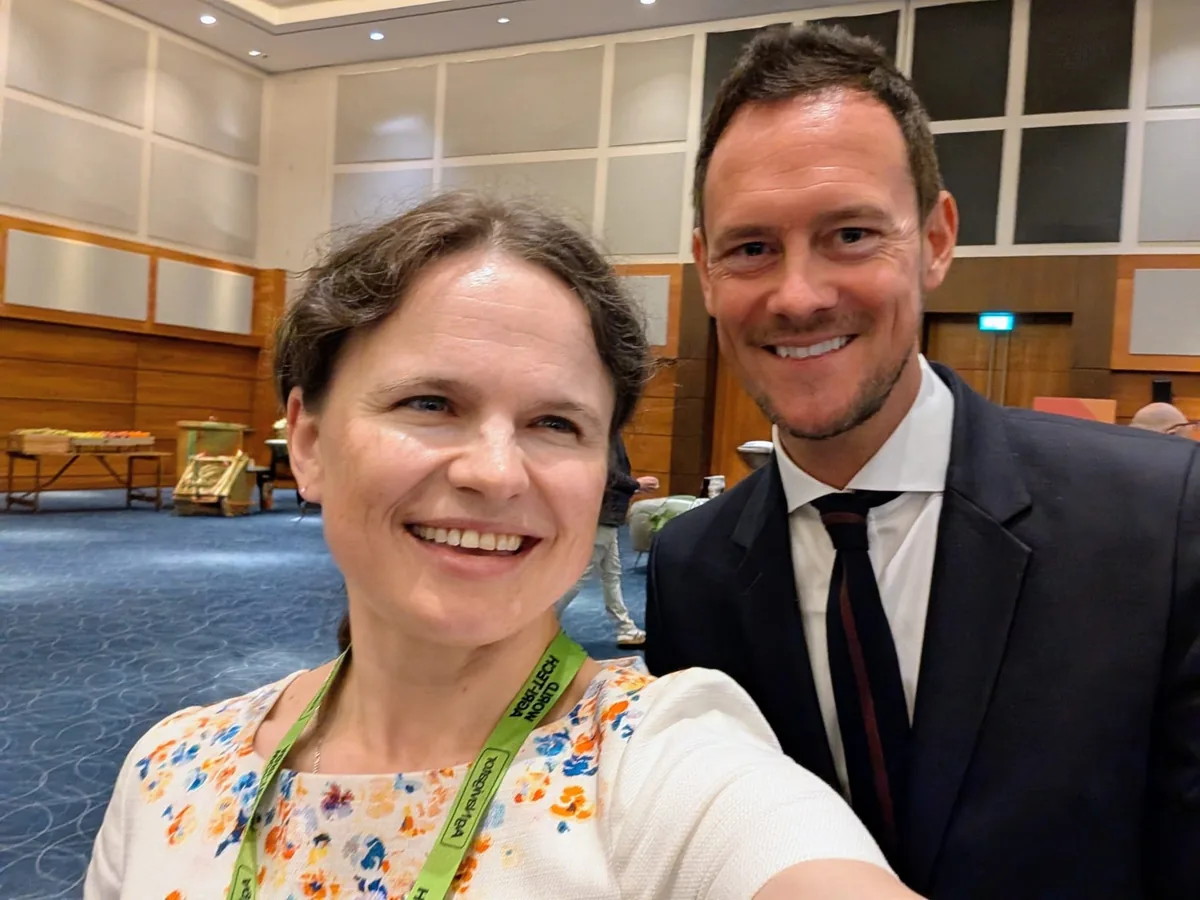 Dr. Maryna Kuzmenko in a selfie with Stephen Morgan MP, who is wearing a dark suit and tie, in a wood-panelled conference foyer.