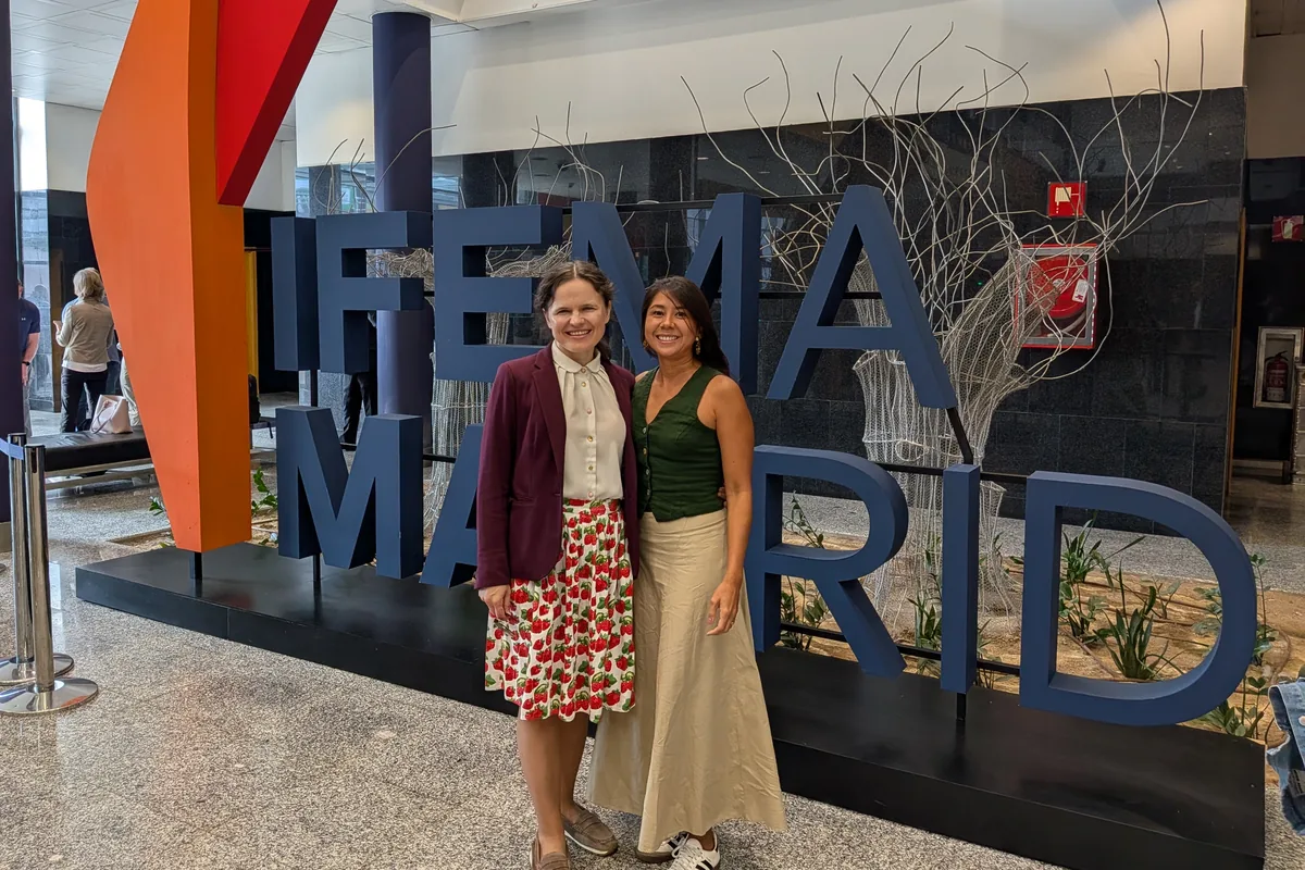 Dr. Maryna Kuzmenko and Juliana Bolanos Castro standing in front of the large IFEMA Madrid letters in the exhibition entrance hall.