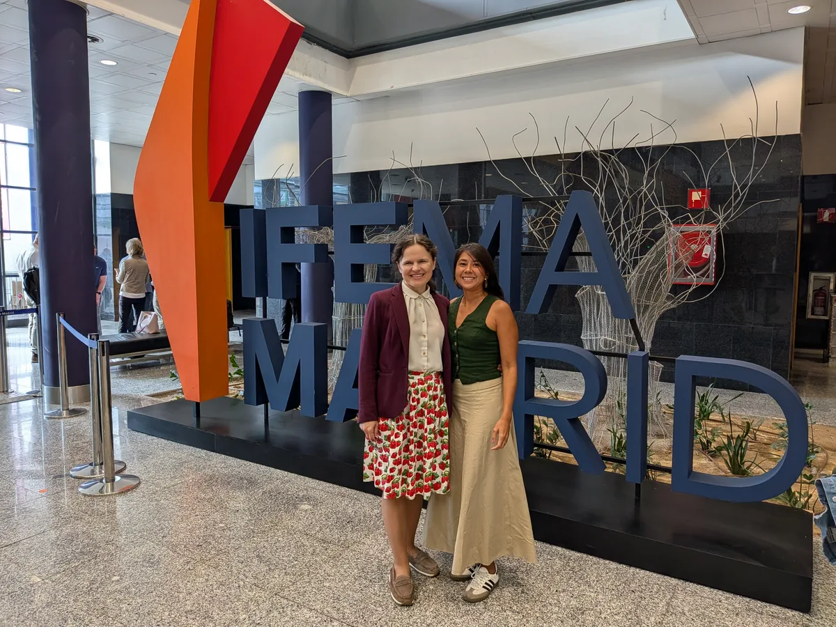 Dr. Maryna Kuzmenko and Juliana Bolanos Castro standing in front of the large IFEMA Madrid letters in the exhibition entrance hall.
