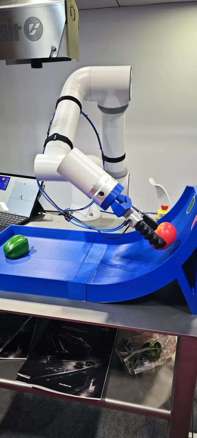A white robot arm mounted over a blue tray, on a stand.